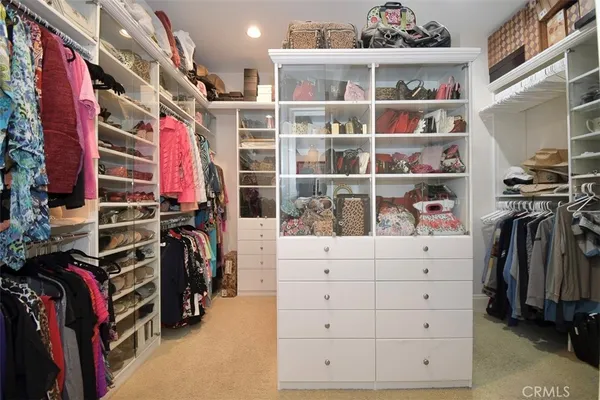 a view of walk in closet with clothes and shoes