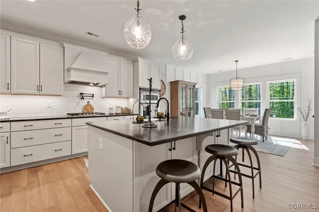 a kitchen with stainless steel appliances kitchen island granite countertop a table chairs sink and cabinets