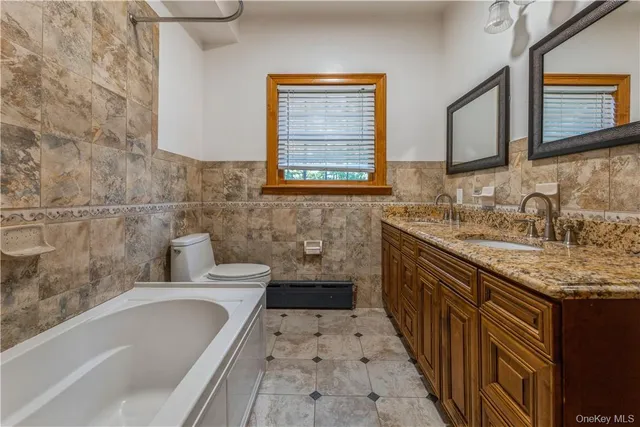 a bathroom with a granite countertop sink a mirror and a bathtub