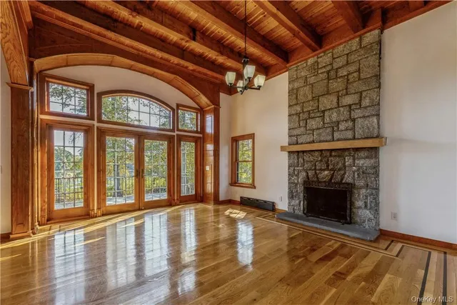 a view of an empty room with wooden floor fireplace and a window