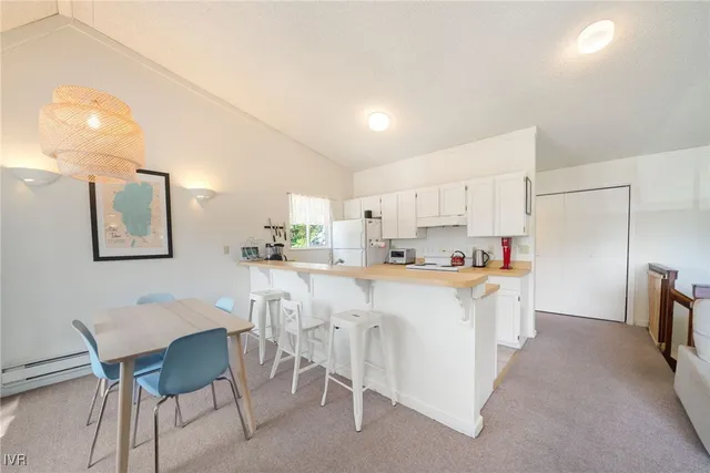 a white kitchen with stainless steel appliances a table and chairs