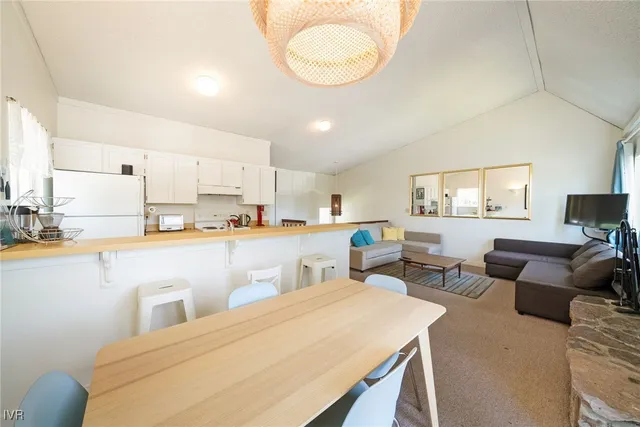 a living room with stainless steel appliances kitchen island granite countertop a sink a stove a dining table and chairs with wooden floor