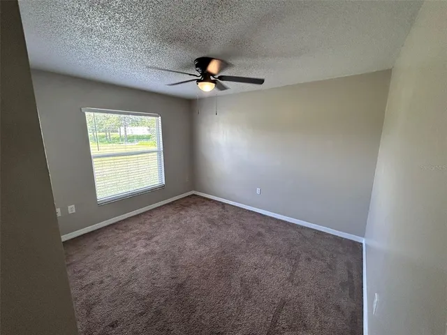 an empty room with windows and fan