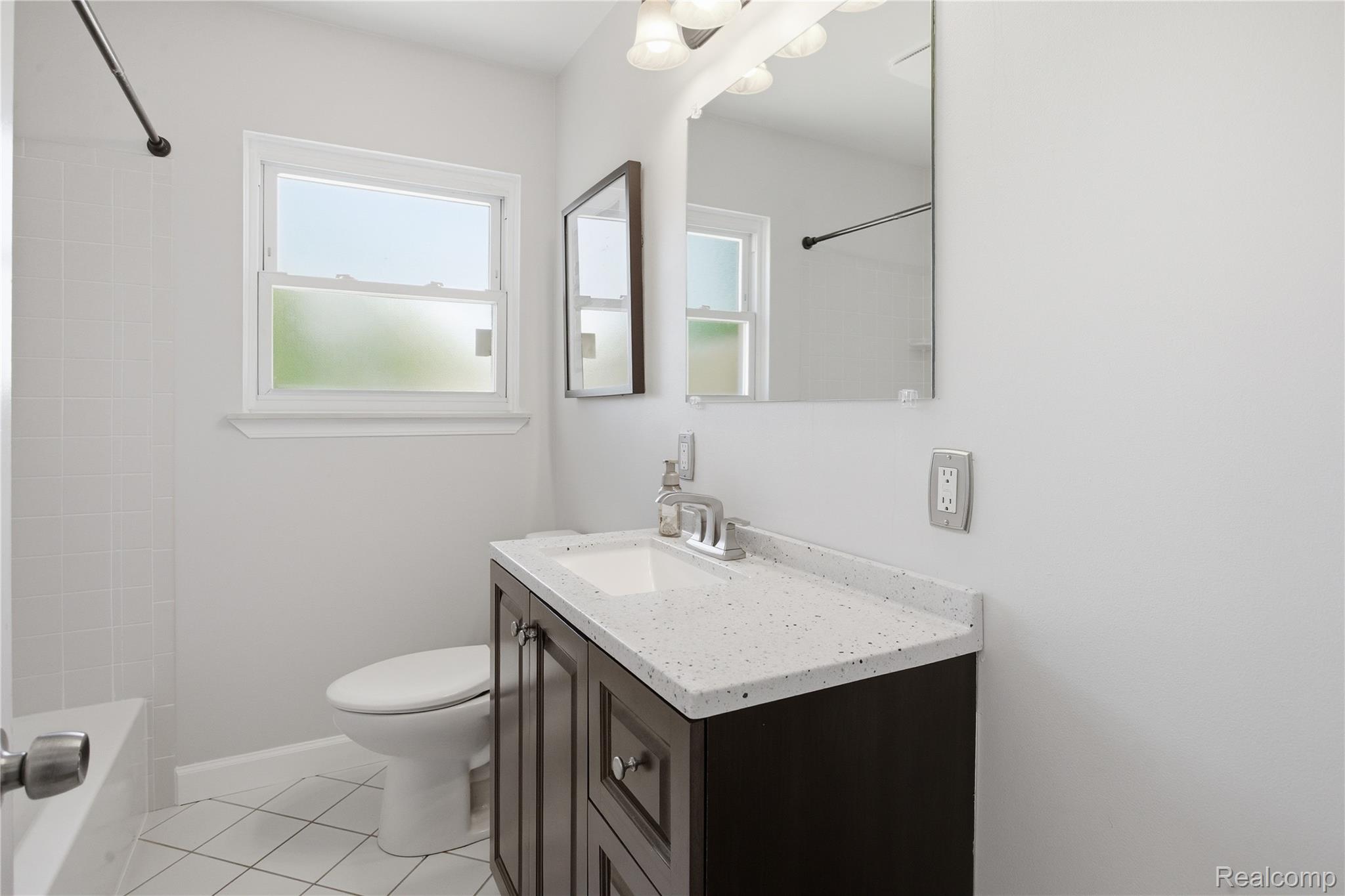 37257 Dundee Street Sterling Heights, MI 48310 - Photo 22 of 47 Bathroom featuring a dark wood-finish vanity with a speckled countertop, an integrated rectangular sink, and chrome fixtures