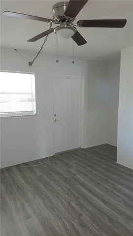 a view of a room with wooden floor fan and windows