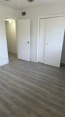 an empty room with wooden floor and mirror