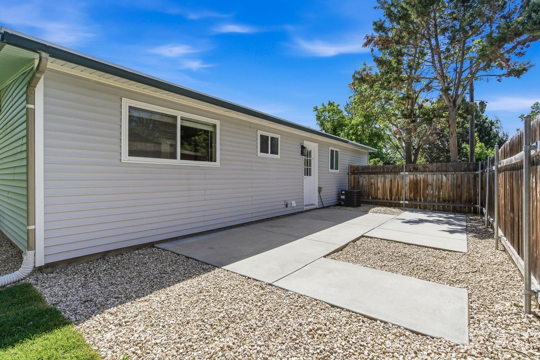 2224 Rachel Circle Boise, ID 83706 - Photo 42 of 50 Low-maintenance side yard featuring light-colored siding, concrete patio areas, gravel landscaping, a wooden privacy fence, and multiple windows