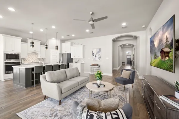 a living room with stainless steel appliances kitchen island granite countertop furniture a rug kitchen view and a chandelier
