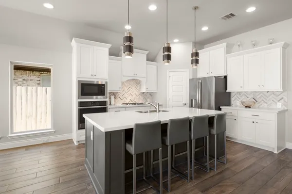 a kitchen with appliances a sink a center island and cabinets