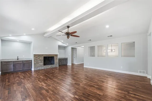 an empty room with wooden floor fireplace and windows