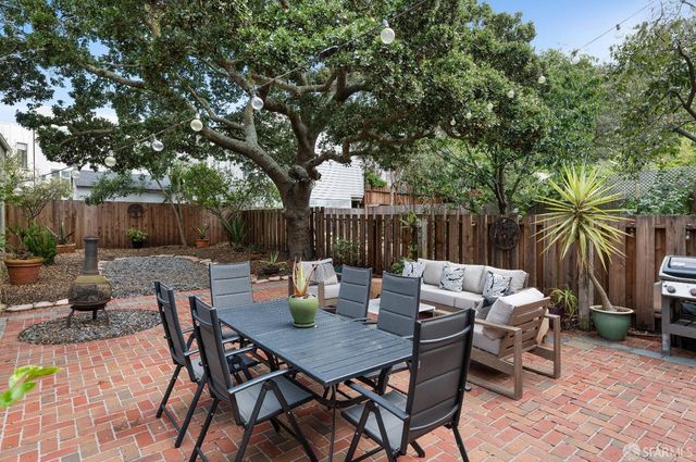 a view of a patio with couches table and chairs and potted plants with wooden floor and fence