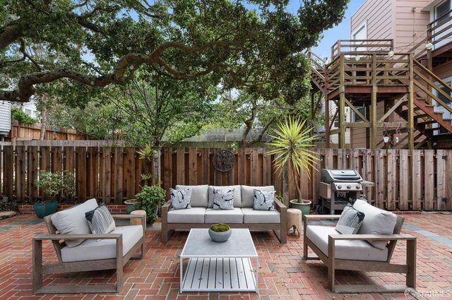 a view of backyard with potted plants and large tree