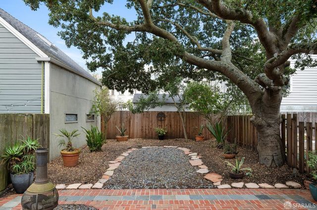 a view of a patio with table and chairs and potted plants with wooden fence