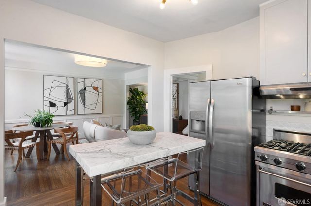 a kitchen with stainless steel appliances granite countertop a table chairs stove and refrigerator