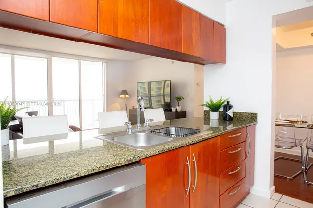 a kitchen with stainless steel appliances granite countertop a sink a stove and a wooden cabinets