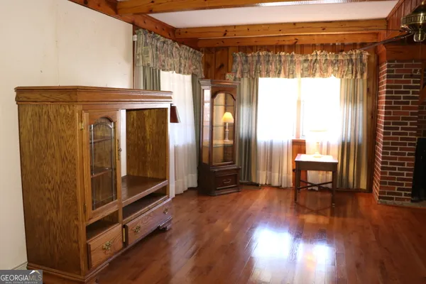a view of an empty room with wooden floor and a ceiling fan