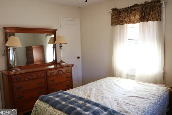 a bedroom with a bed and a lamp on the dresser