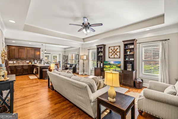 a kitchen with granite countertop a stove a sink a dining table and chairs with wooden floor