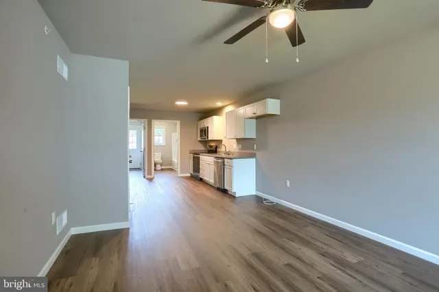 a kitchen with granite countertop a stove top oven a sink dishwasher and a microwave oven on the wooden floor