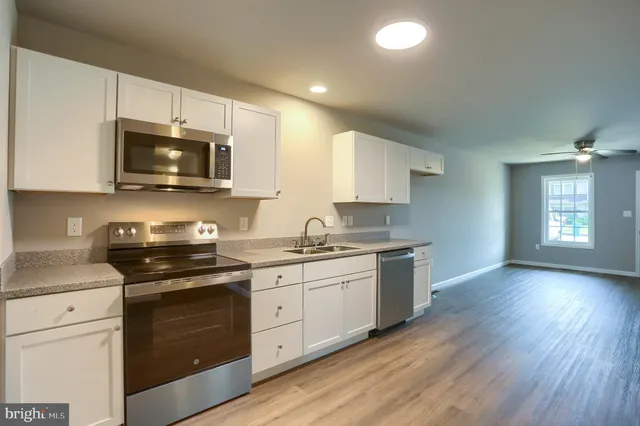 a kitchen with a refrigerator a sink dishwasher a stove and white cabinets with wooden floor