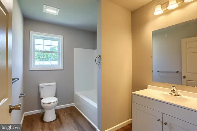 a view of an empty room with wooden floor and closet