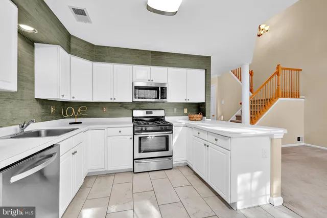 a kitchen with white cabinets appliances and a sink