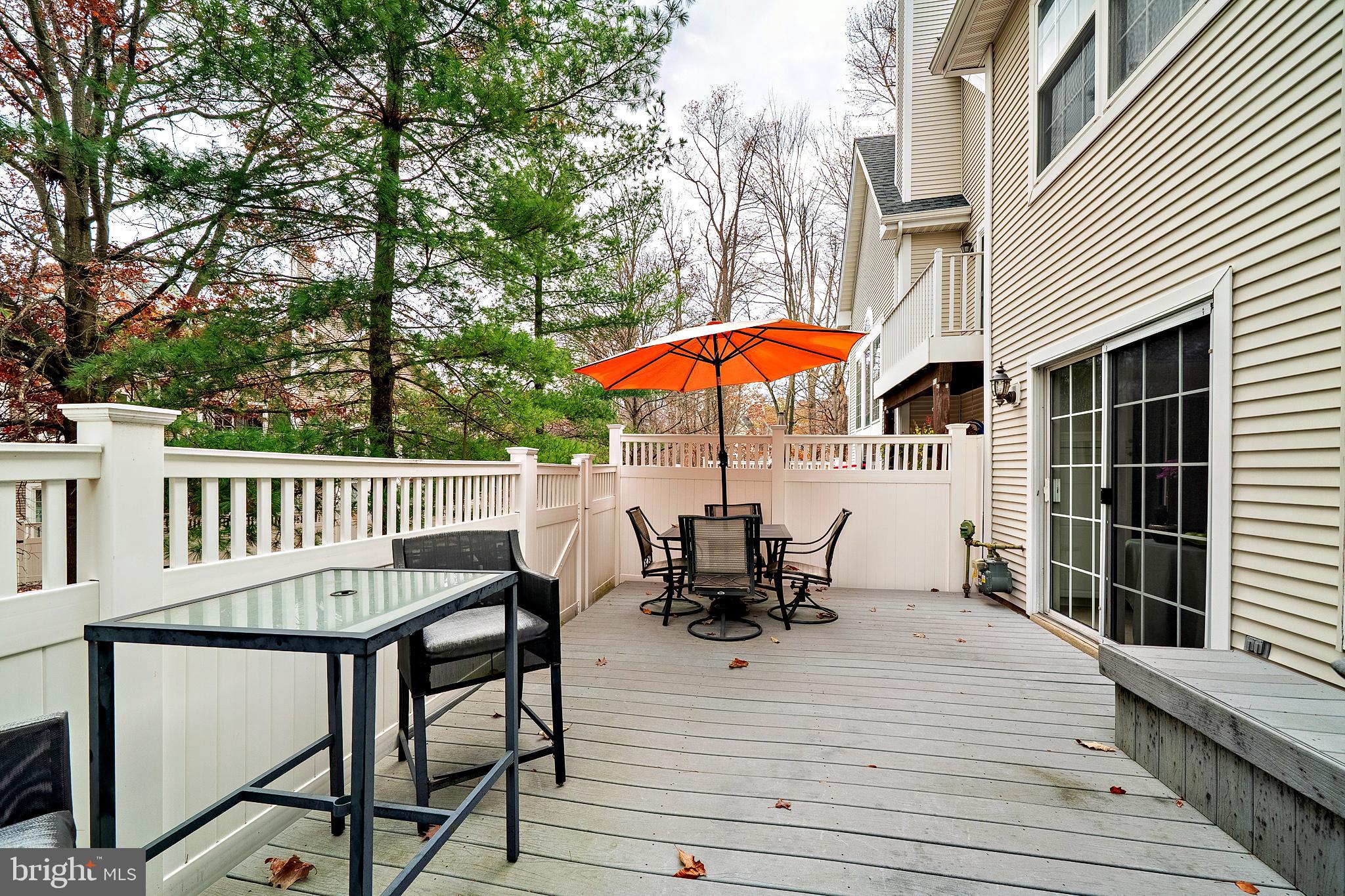 305 Deer Run Court Pennington, NJ 08534 - Photo 33 of 34 a view of a roof deck with table and chairs under an umbrella with wooden floor and fence