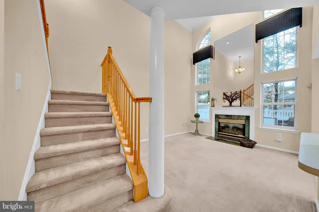 a view of an empty room with fireplace stairs and windows