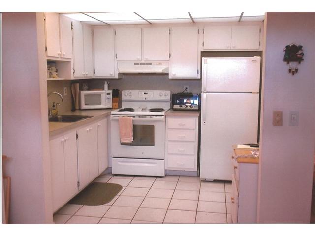 409 Saxony Way, Unit 409 Delray Beach, FL 33446 - Photo 4 of 8 a kitchen with white cabinets and white appliances