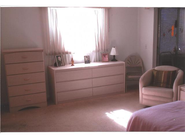 409 Saxony Way, Unit 409 Delray Beach, FL 33446 - Photo 5 of 8 a bedroom with a bed and a chair