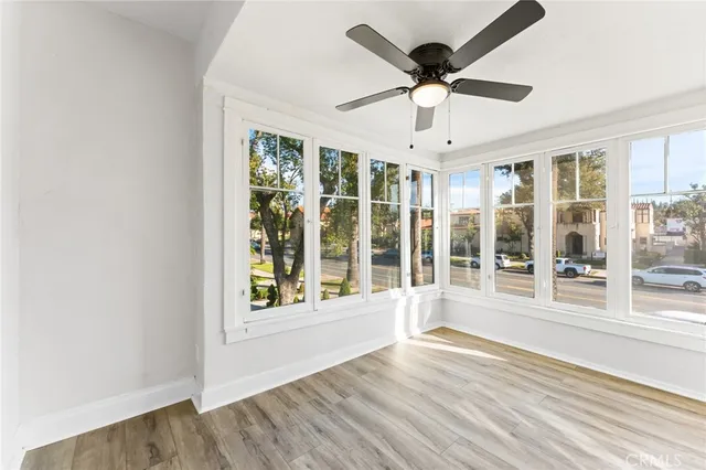 a view of an empty room with wooden floor and a window