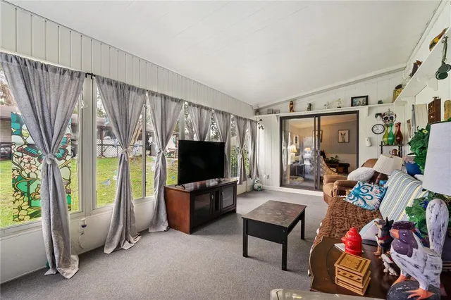 a living room with furniture a flat screen tv and a floor to ceiling window