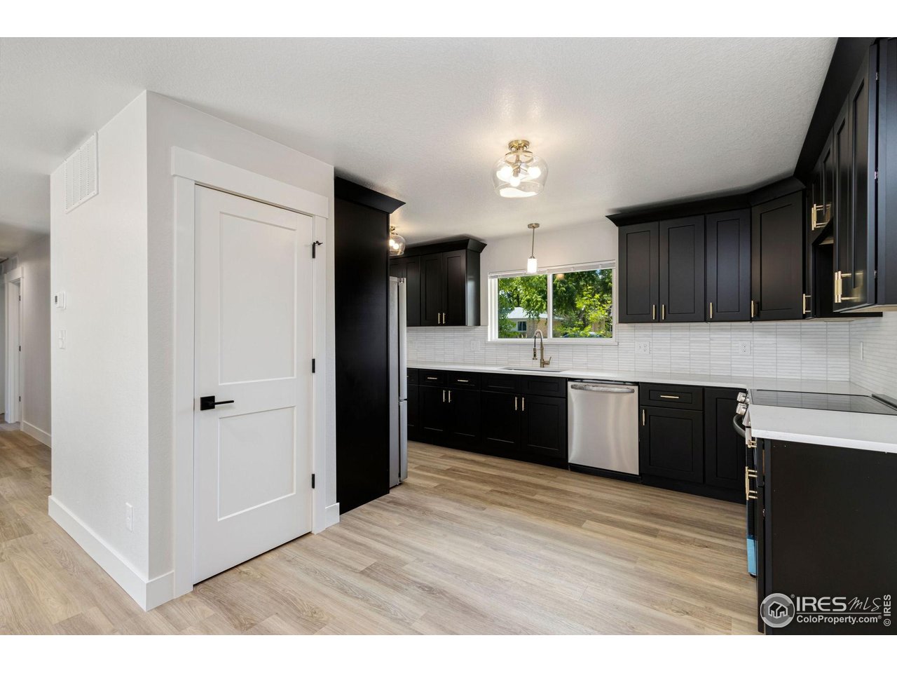 812 Rocky Road Fort Collins, CO 80521 - Photo 4 of 19 a kitchen with granite countertop a refrigerator cabinets and wooden floor