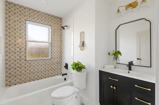 a bathroom with a bathtub sink vanity mirror and toilet