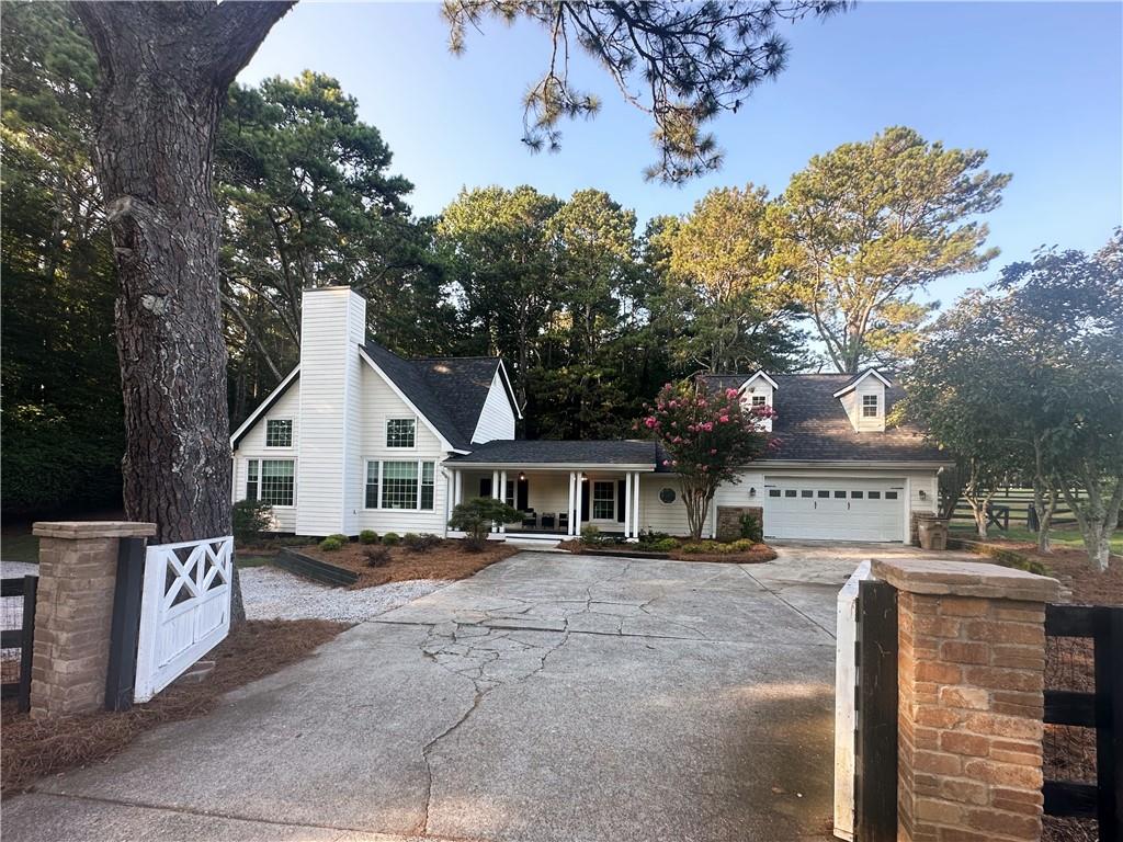 a view of a white house next to a yard with a fountain and large trees