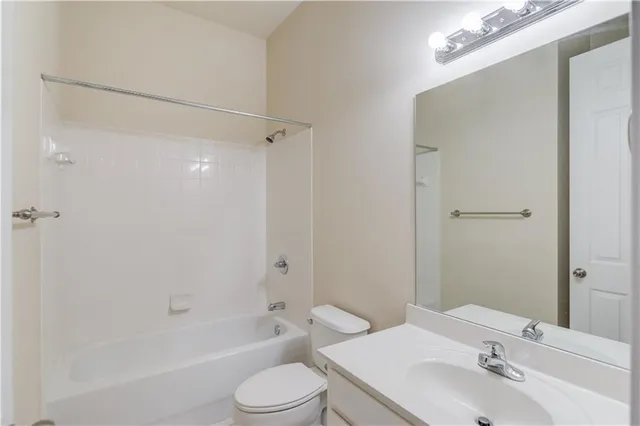 a bathroom with a bathtub shower sink vanity mirror and toilet