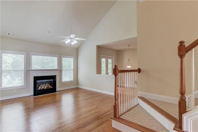 an empty room with wooden floor fireplace and windows