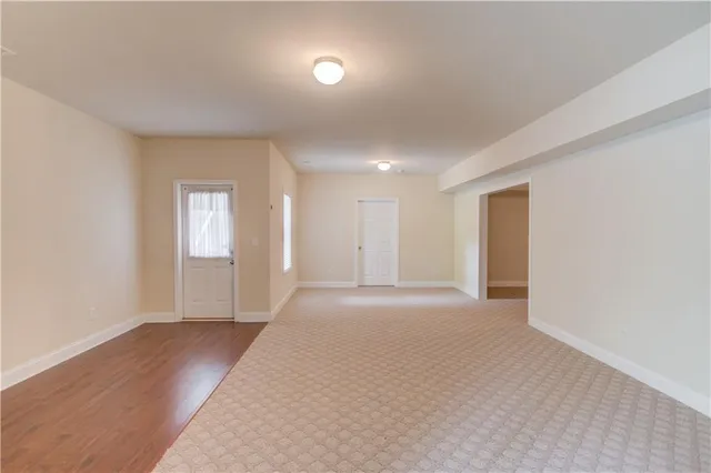 a view of an empty room with wooden floor and closet