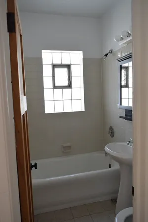 a bathroom with a bathtub a window and a shower