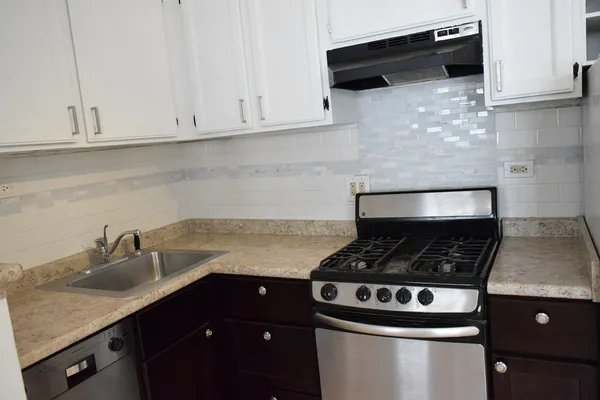 a kitchen with granite countertop a stove and a white cabinets