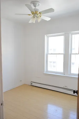 an empty room with a window and a fan