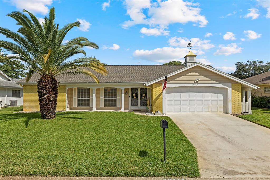 12111 Fieldstone Lane Hudson, FL 34667 - Photo 1 of 49 a front view of a house with a garden and trees