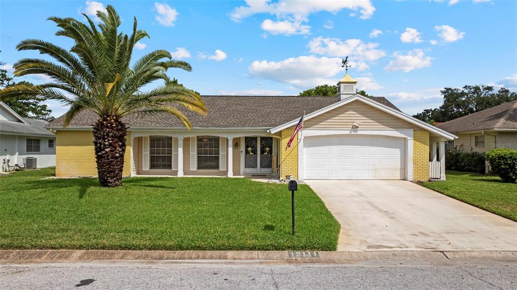 12111 Fieldstone Lane Hudson, FL 34667 - Photo 30 of 49 a front view of a house with a garden and trees