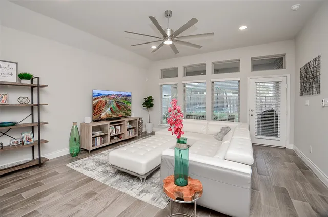 a living room with furniture a flat screen tv and a floor to ceiling window