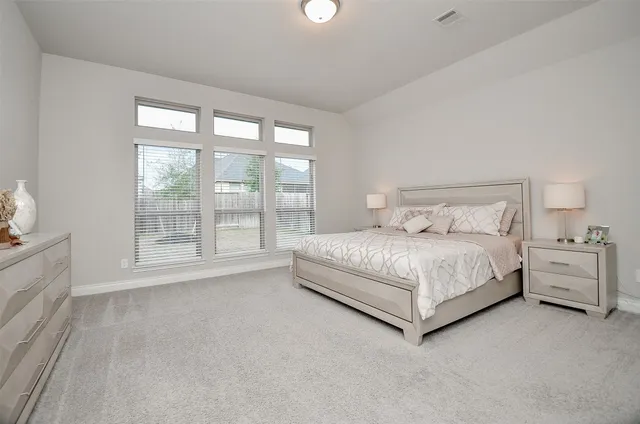 a spacious bedroom with a bed and a lamp