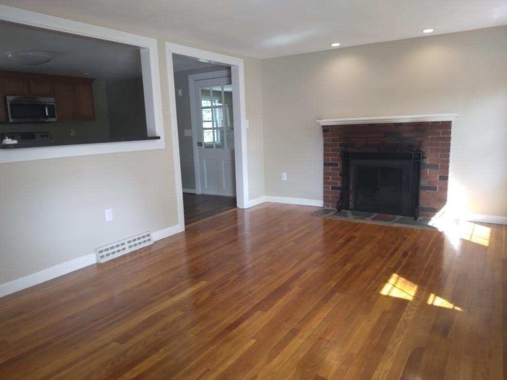 42 Lowell Road Pepperell, MA 01463 - Photo 12 of 32 a view of an empty room with wooden floor and a fireplace