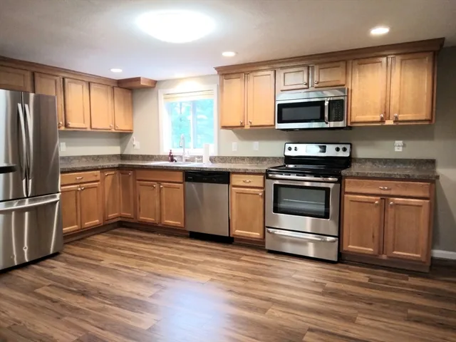 a kitchen with granite countertop a sink stainless steel appliances and cabinets