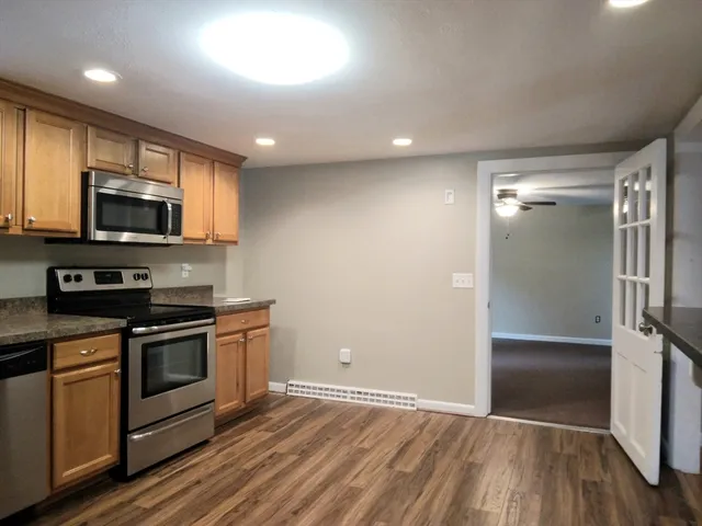 a view of kitchen with stainless steel appliances wooden floor stove and a refrigerator