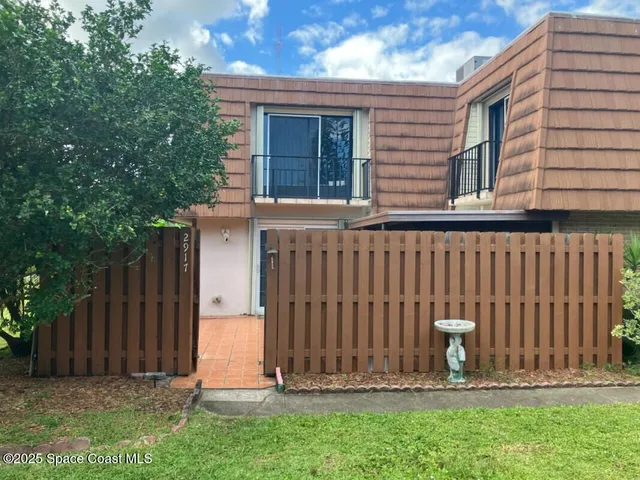 a view of a house with a small yard and wooden fence