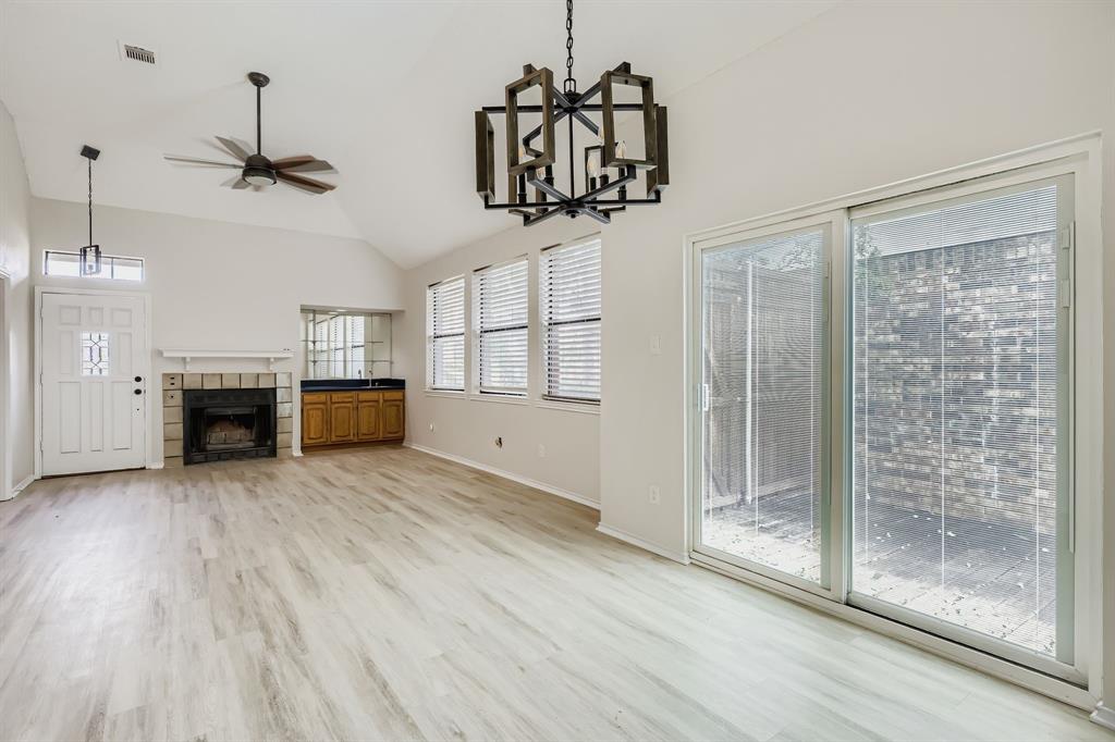 4319 Harvest Hill Road Carrollton, TX 75010 - Photo 13 of 28 Unfurnished living room with a chandelier, light wood-style floors, high vaulted ceiling, a tiled fireplace, and a ceiling fan